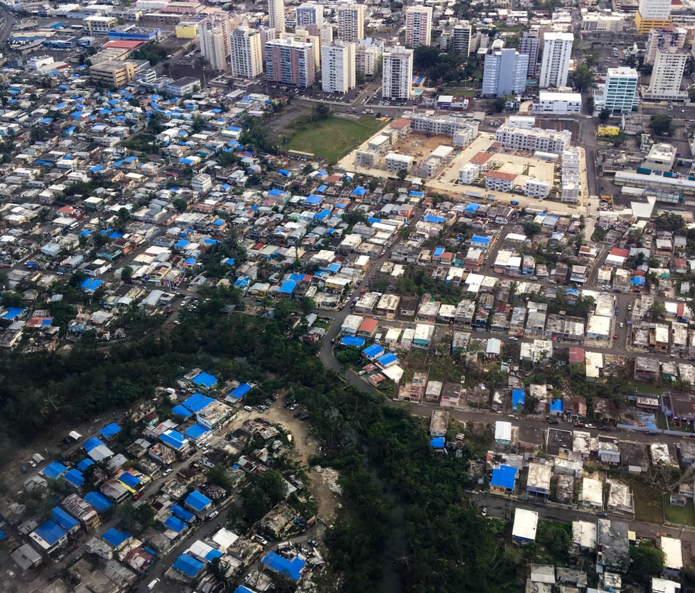 Aerial shot showing blue tarpaulin roofs of destroyed homes in San Juan, Puerto Rico